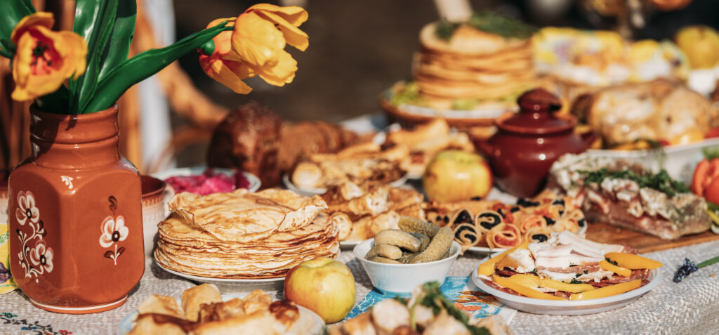 Dishes of the traditional Belarusian cuisine - pancakes, pancakes with caviar, lard, bacon, honey and pickled cucumbers. Attribute of traditional folk celebration of Maslenitsa. Panorama, Panoramic View